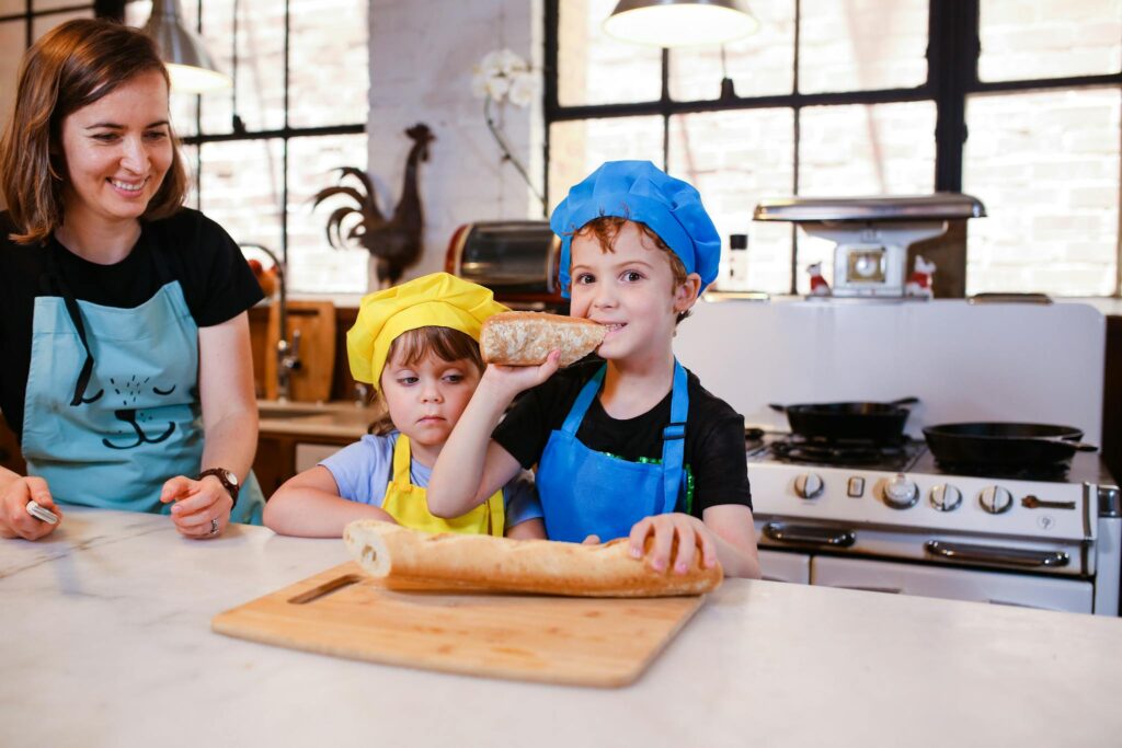 A Boy in a Chef Hat Eating Bread